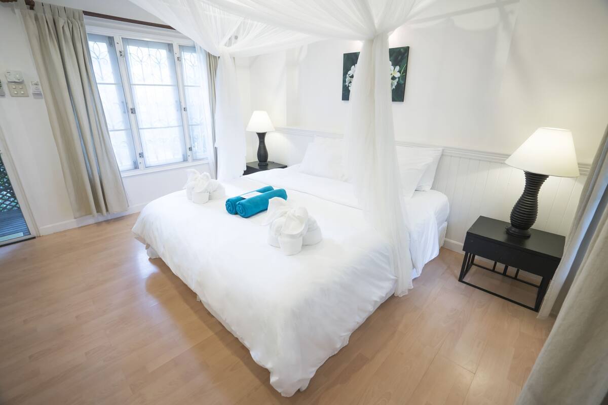 Ein Hotelzimmer mit Himmelbett, zwei Nachttischen und Blick ins Freie.