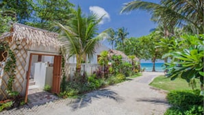 A pathway leading to a thatched-roof structure surrounded by lush greenery and palm trees. - King's Garden Resort (Koh Samui)