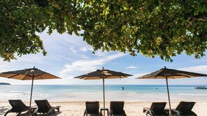 A beach with three umbrellas and four lounge chairs. - King's Garden Resort (Koh Samui)