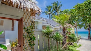 A beachfront property with a thatched roof, palm trees, and a clear view of the ocean. - King's Garden Resort (Koh Samui)