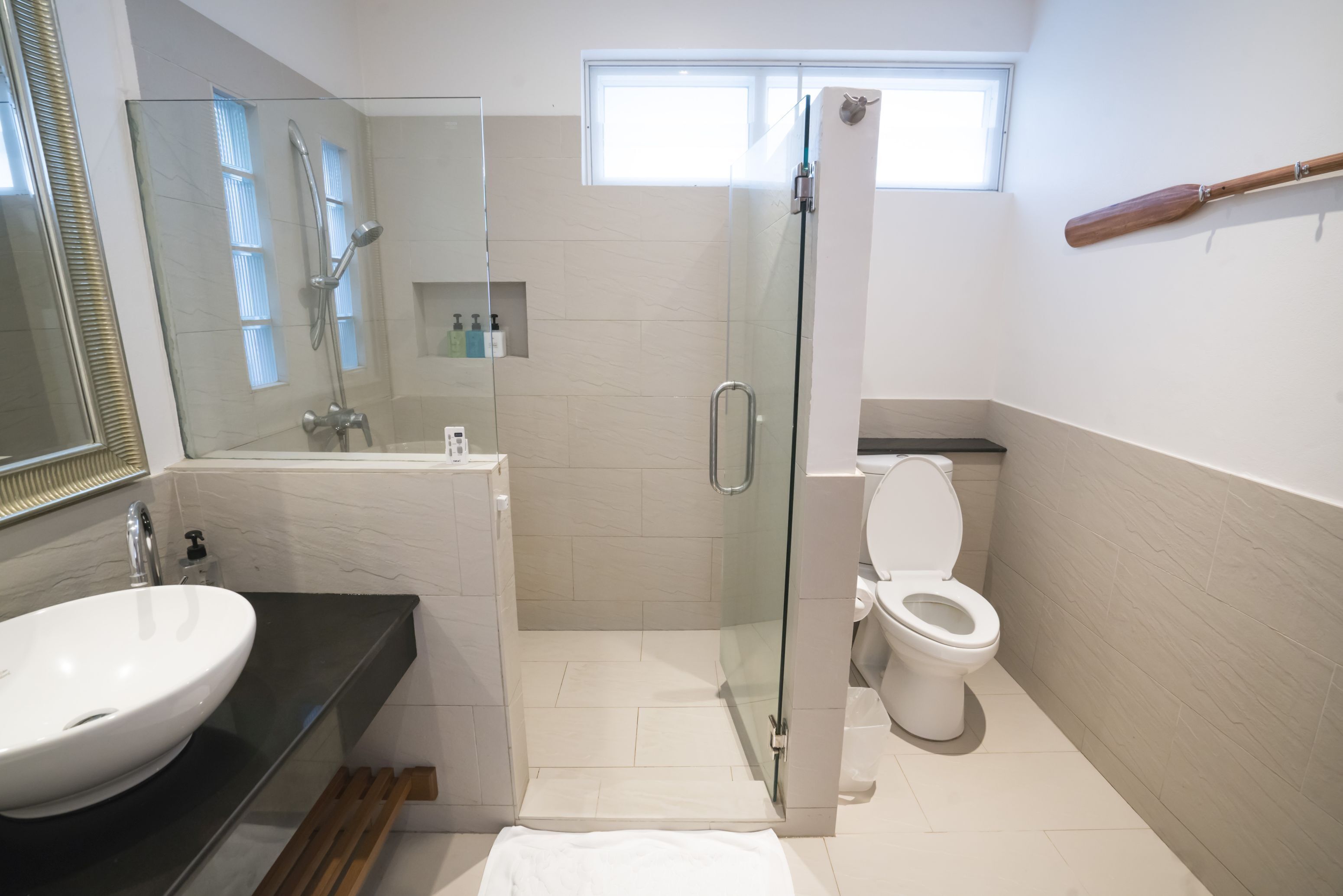 A modern bathroom with a glass-enclosed shower, a white sink, and a toilet.