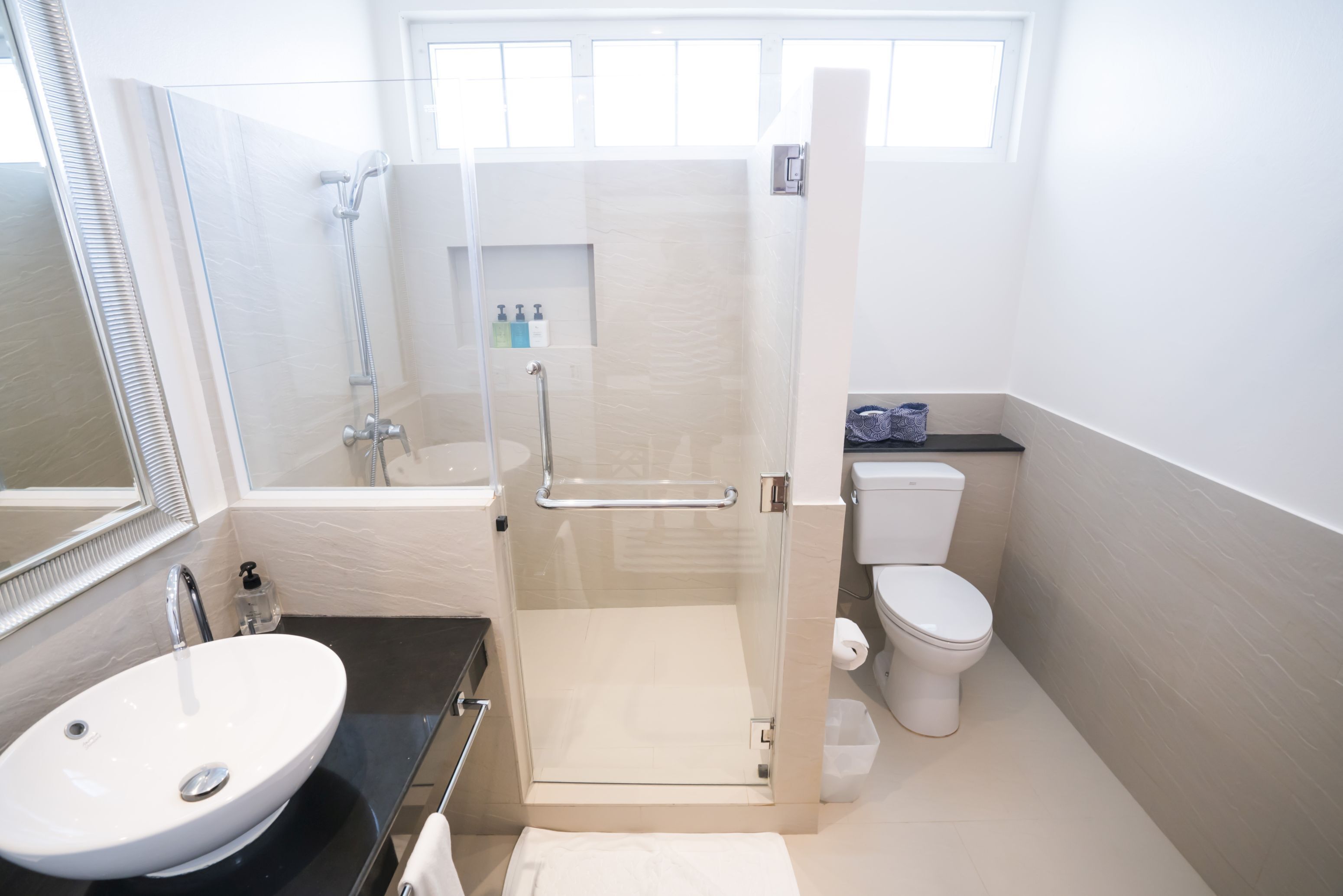 A modern bathroom with a glass-enclosed shower, a white sink, and a toilet.