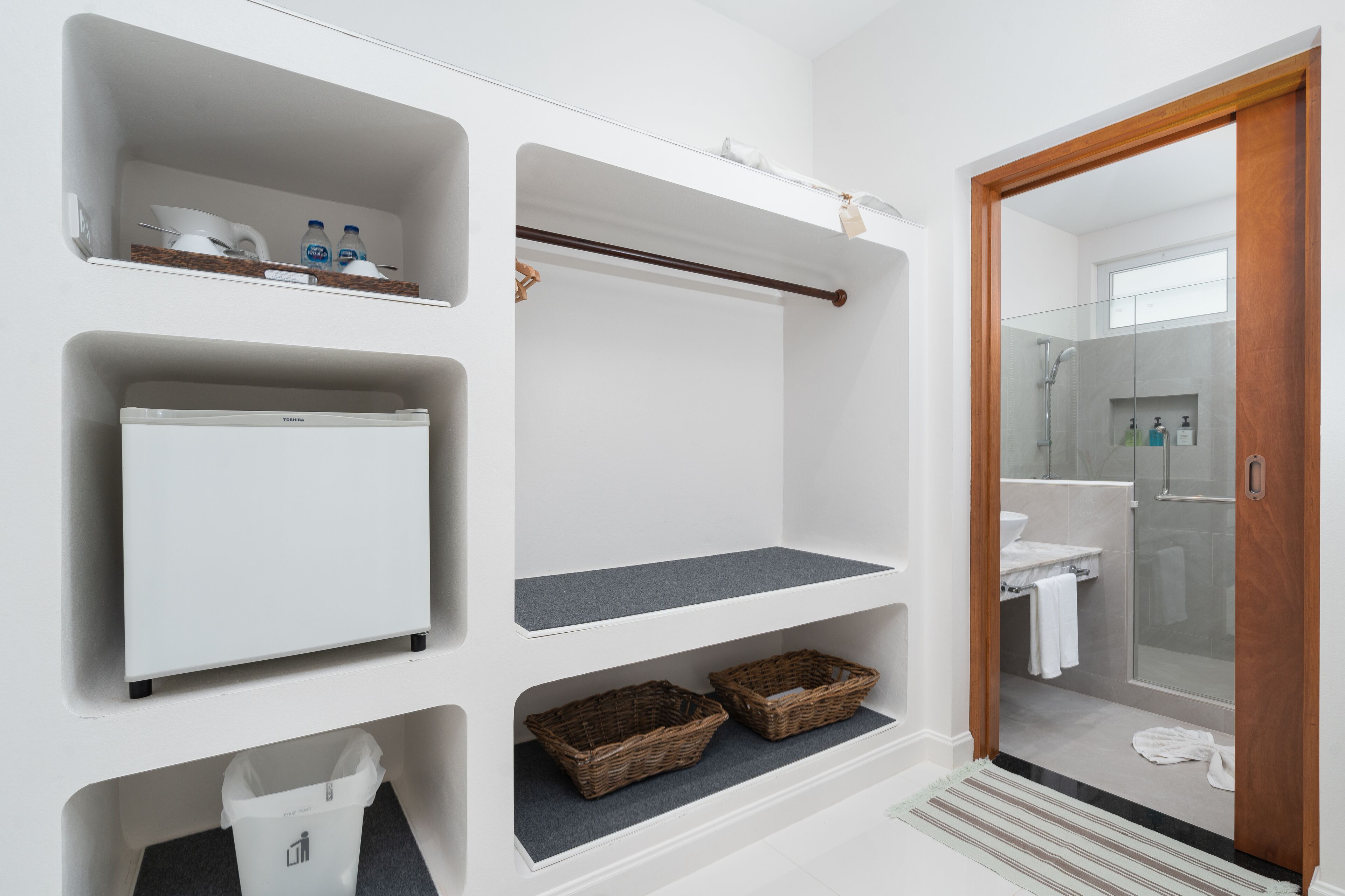 A bathroom with white cabinetry, a towel rack, a shower area, and a toilet.