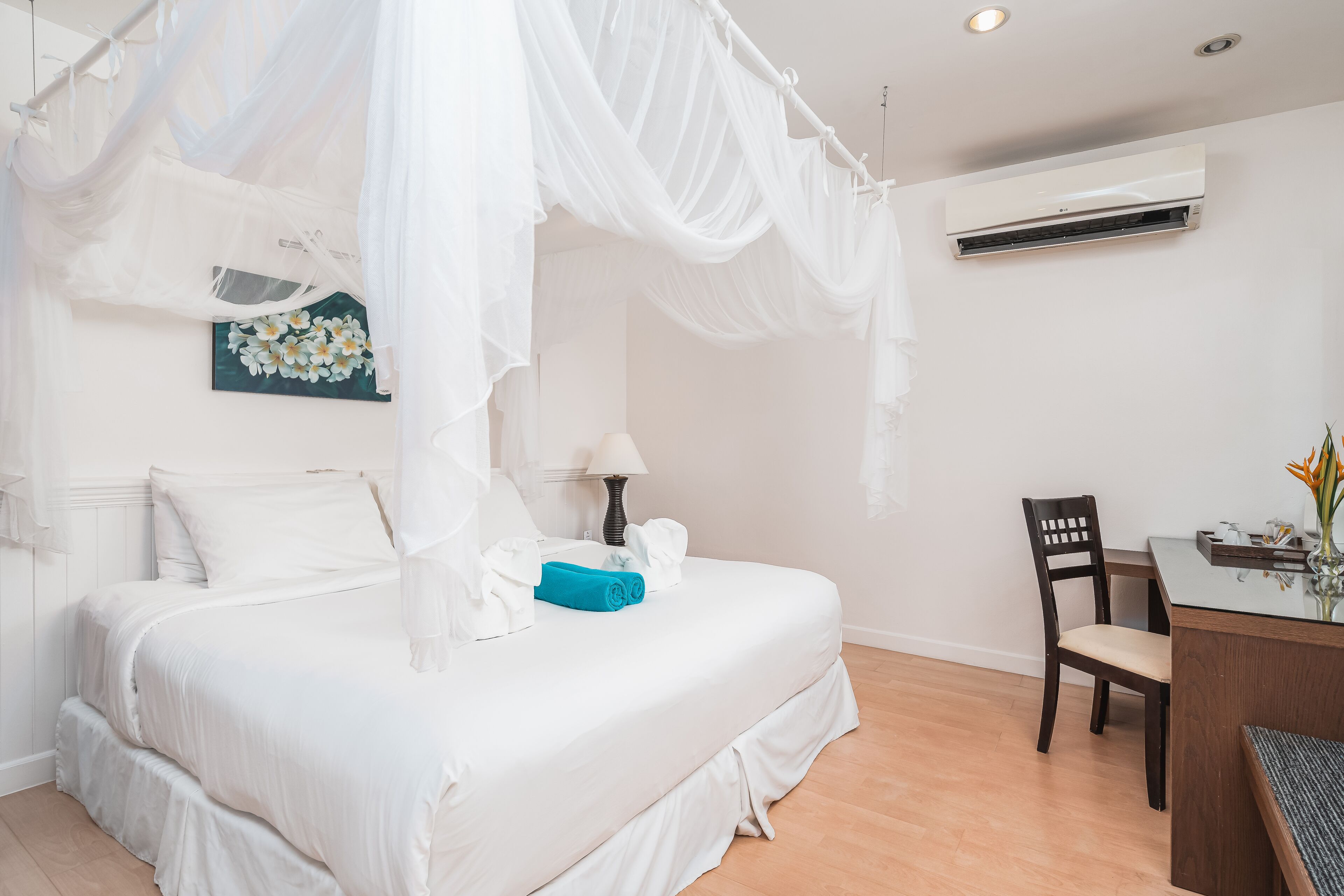 A bedroom with a canopy bed, a desk, and an air conditioning unit.