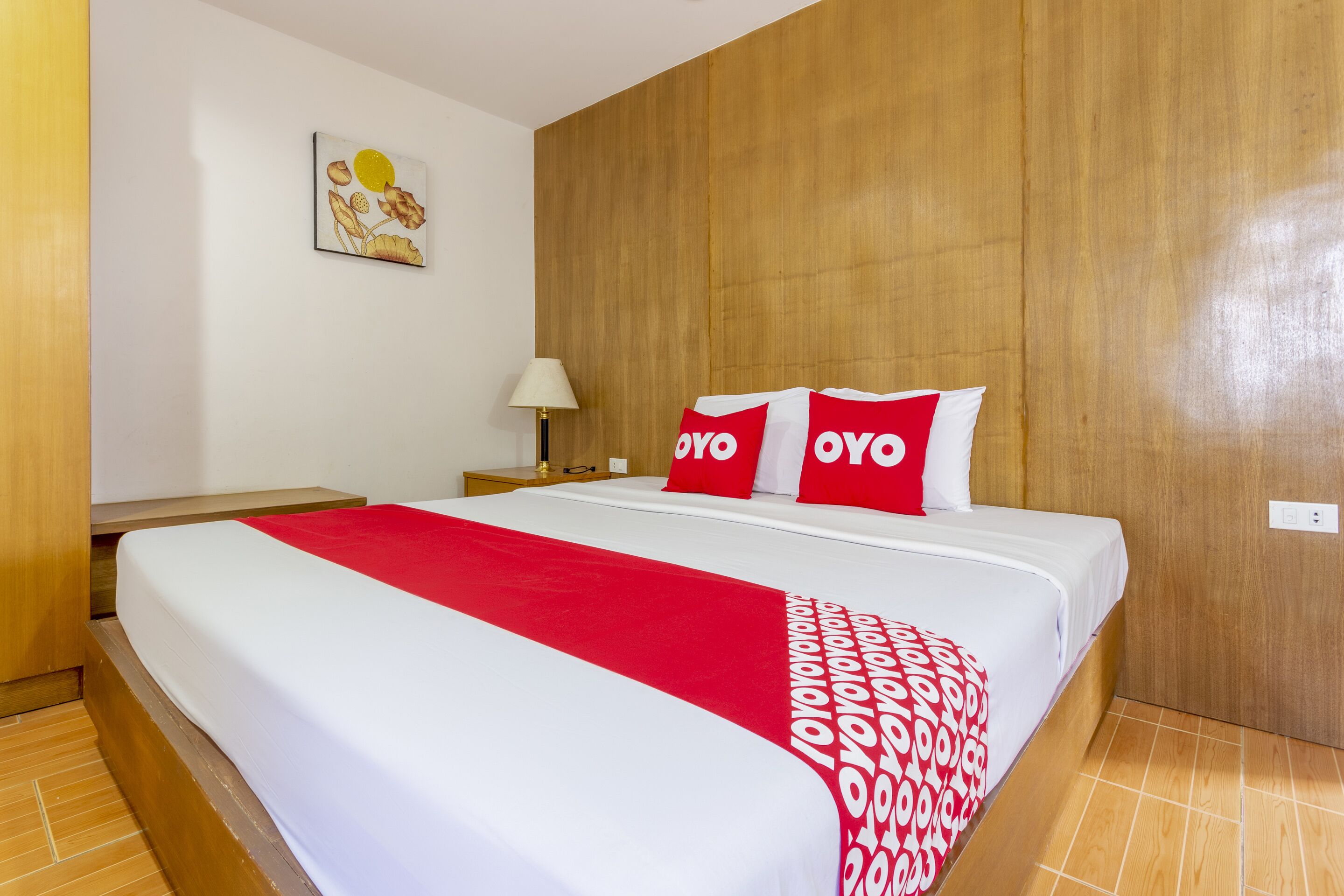 A hotel room with a bed, a nightstand, a lamp, and a wooden headboard.