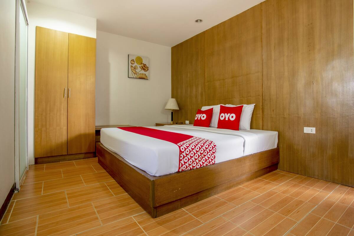 A bedroom with a wooden bed, a red and white patterned blanket, and two red pillows with "YOYO" text.