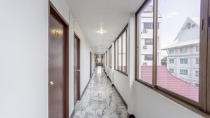 A corridor with marble flooring, wooden doors, and large windows offering views of buildings. - Super OYO 1096 Winner Inn Hotel (Chiang Mai)