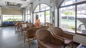 A spacious lobby with wicker chairs, a sofa, and large windows offering views of the street. - Super OYO 1096 Winner Inn Hotel (Chiang Mai)