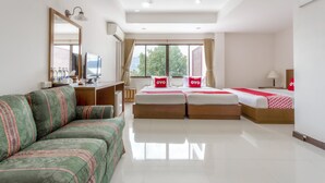 A hotel room with a sofa, two beds with red bedding, a TV, and a large window with curtains. - Super OYO 1096 Winner Inn Hotel (Chiang Mai)