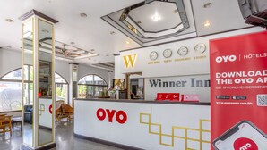 A hotel reception area with a prominent 'OYO' logo, a digital clock, and a sign advertising a mobile app. - Super OYO 1096 Winner Inn Hotel (Chiang Mai)