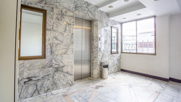 A marble-floored lobby with an elevator, a trash bin, and large windows. - Super OYO 1096 Winner Inn Hotel (Chiang Mai)