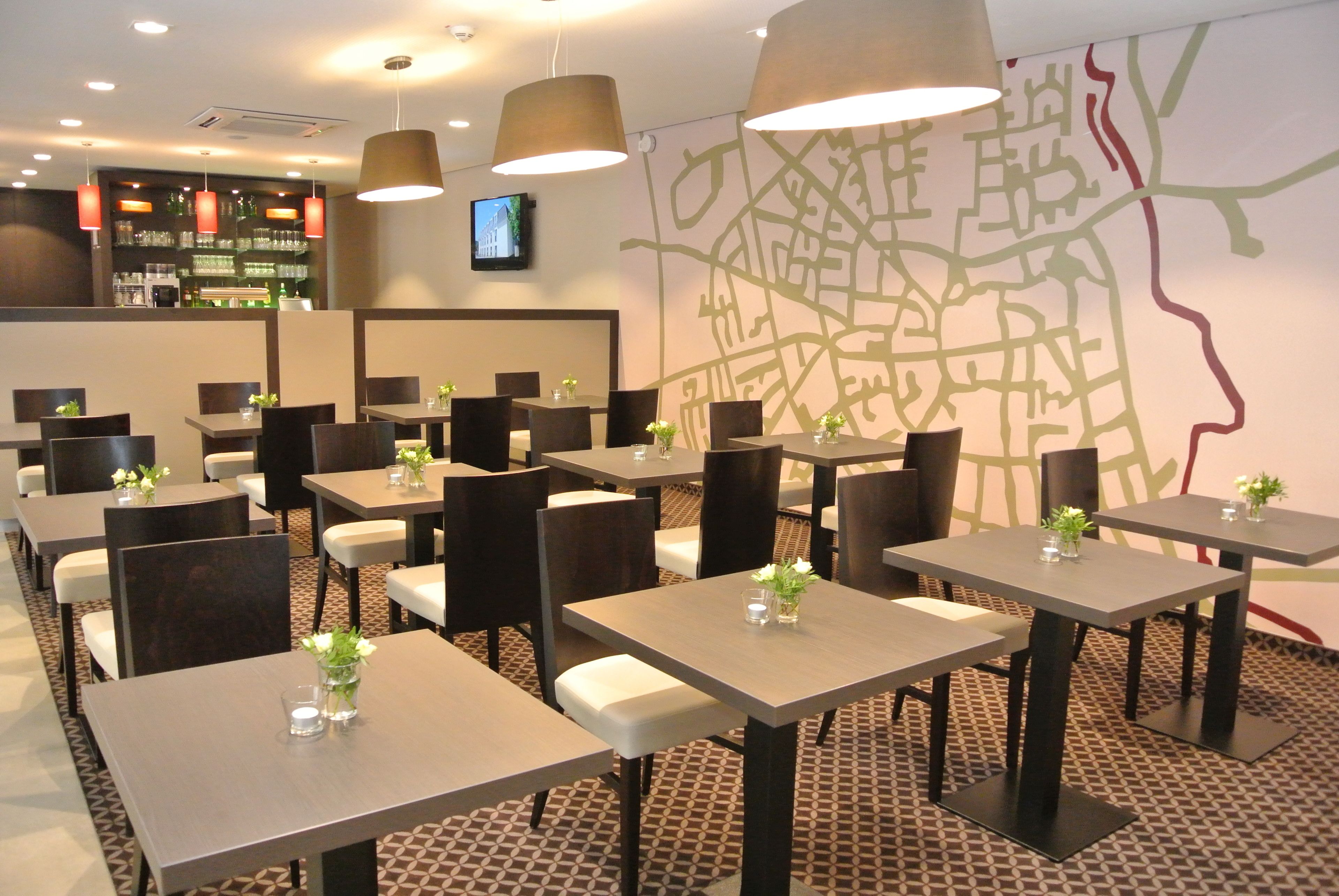 A restaurant with multiple tables and chairs, a map on the wall, and a bar area in the background.