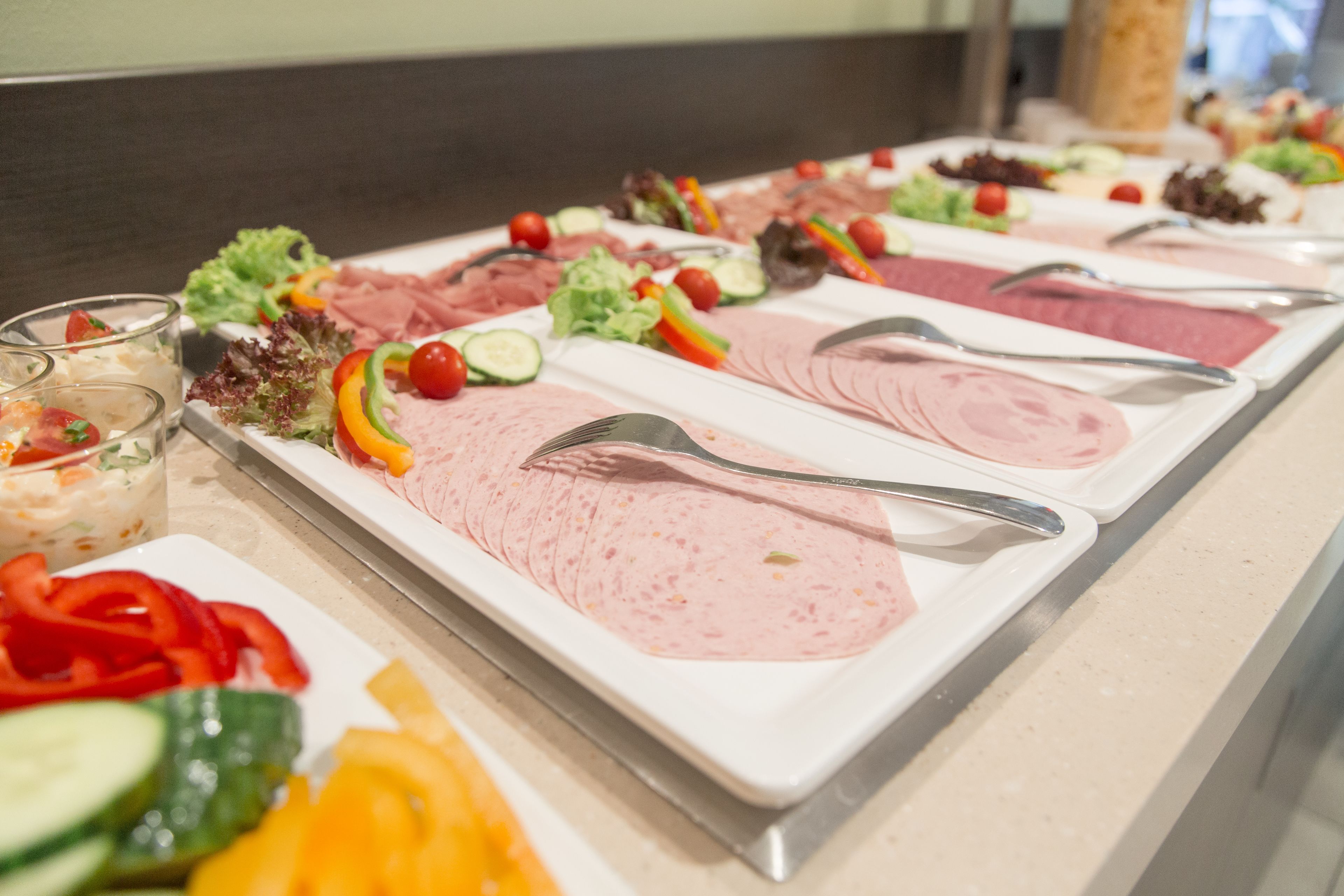 Ein Buffet mit verschiedenen Speisen, darunter Fleisch, Gemüse und Salate.