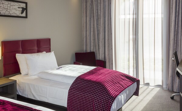 A hotel room with a bed, a nightstand, a chair, a desk, and a window with curtains. - Hotel zur Krone (Gescher)