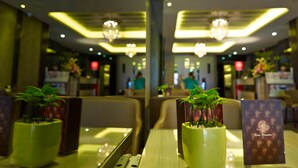 L’intérieur d’un restaurant, avec des tables, des chaises et des lustres suspendus au plafond.