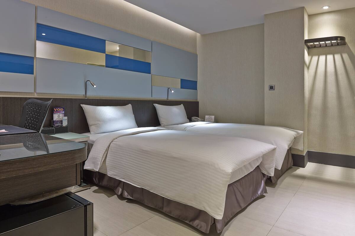 Een moderne hotelkamer met een groot bed, een bureau met stoel, een telefoon en een minibar.