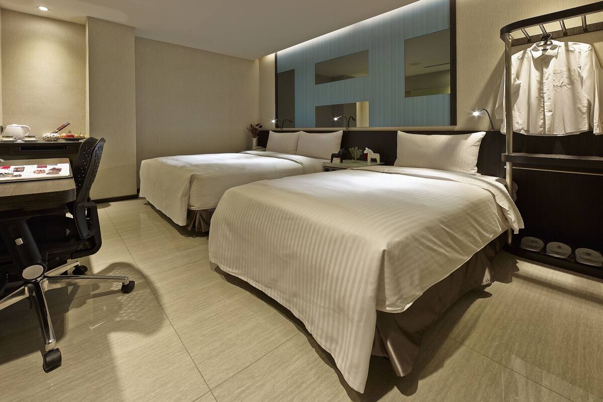 Een hotelkamer met twee bedden, een bureau en een kledingkast.