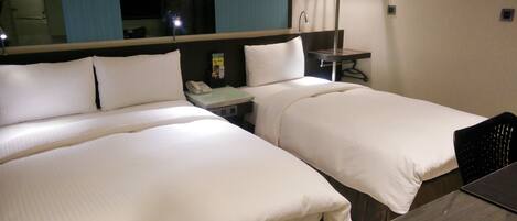 A hotel room with two beds, a desk, a lamp, and a telephone.