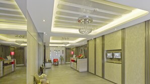 Un hall d’hôtel moderne avec un comptoir d’accueil, un espace salon et un grand lustre.