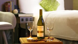 Une bouteille de Santa Helena Chardonnay 2011 sur une table de chevet, accompagnée de deux verres à vin vides et d’une bougie allumée.