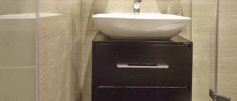 A modern bathroom with a large sink, a mirror, and a glass shower enclosure.