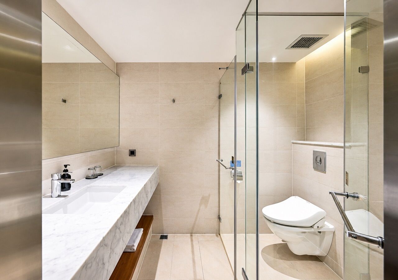 Un bagno moderno con doccia vetro, lavandino bianco e WC.