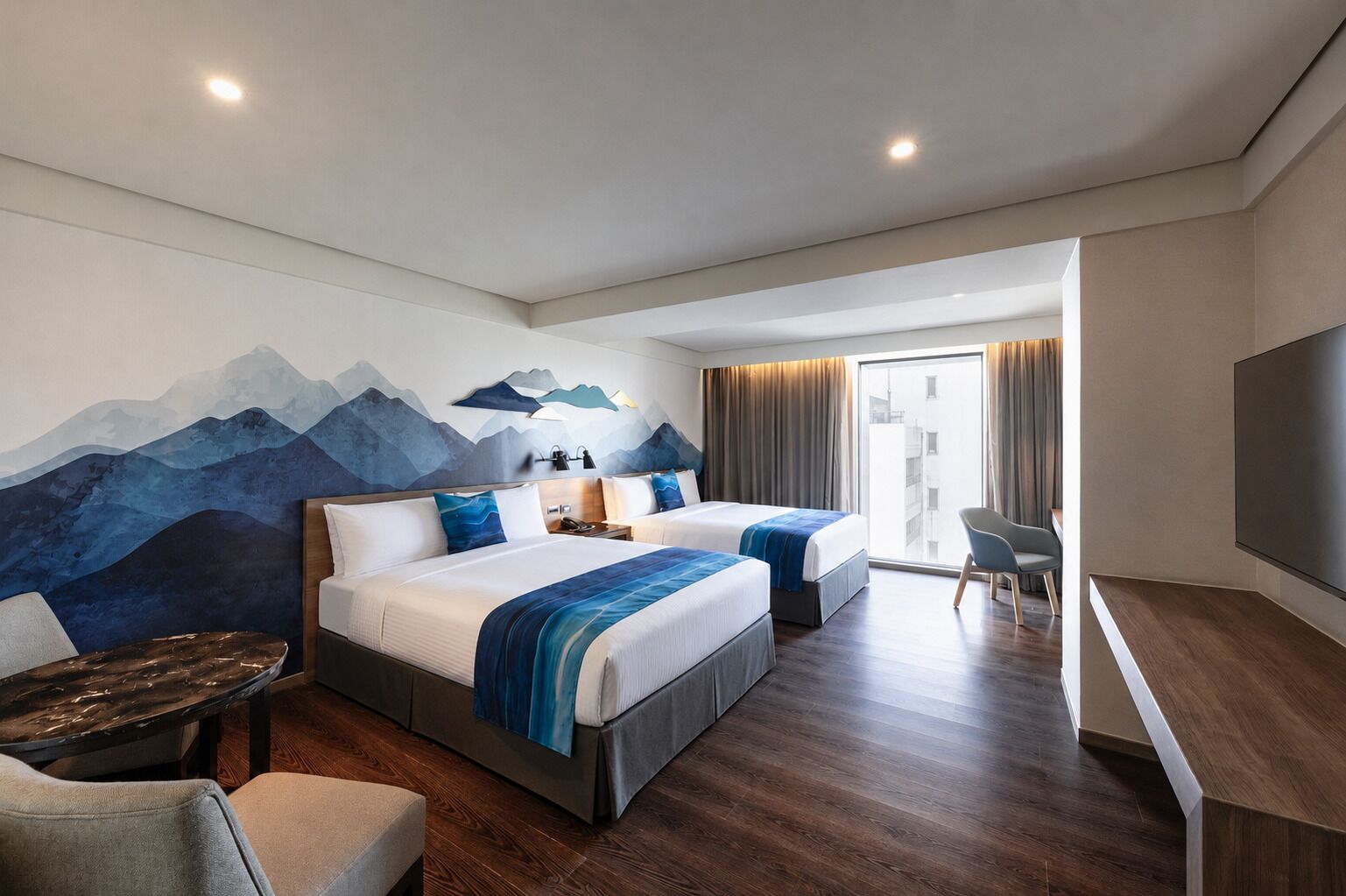 A hotel room with two beds, a desk, a chair, a TV, and a large window.