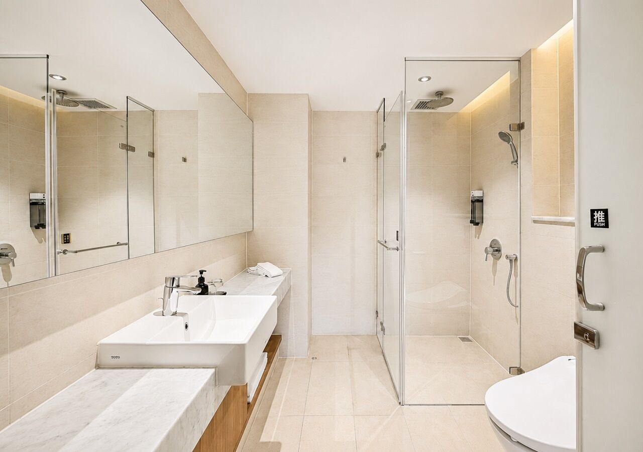 Un baño moderno con tocador doble, cabina de ducha con mampara de vidrio y retrete.