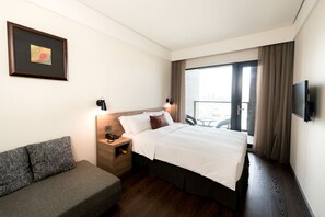 A hotel room with a bed, a sofa, a bedside table with a lamp, a TV, and a window with curtains. - Just Sleep Hualien Zhongzheng (Hualien City)