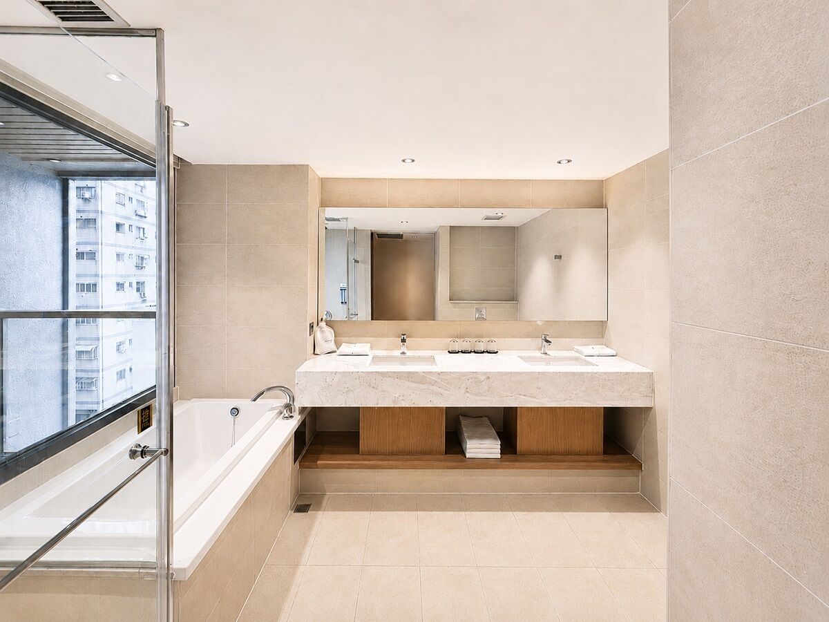 Un baño moderno con un espejo grande, una bañera y un lavamanos.