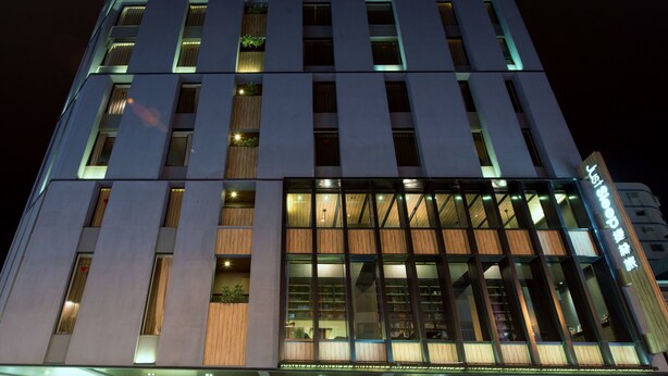 A modern hotel with a prominent glass facade, multiple floors, and a sign indicating it is a sleepover facility. - Just Sleep Hualien Zhongzheng (Hualien City)
