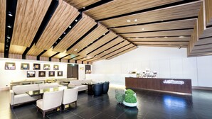 A modern hotel lobby with a reception desk, seating area, and decorative plants. - Just Sleep Hualien Zhongzheng (Hualien City)