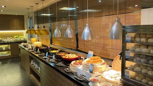 A buffet area with various dishes, utensils, and a food display case. - Just Sleep Hualien Zhongzheng (Hualien City)