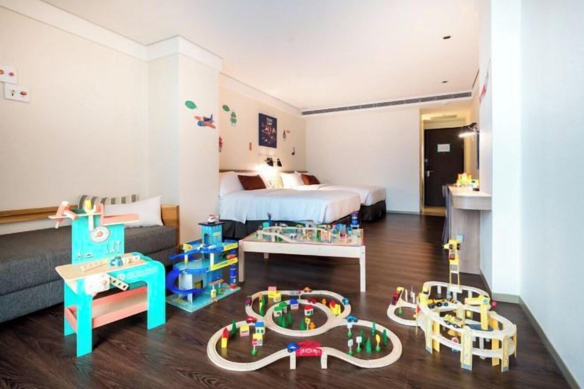 A child-friendly room with a play area, a bed, and a desk.