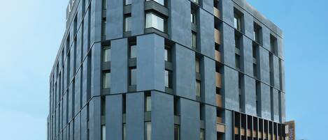 A modern building with a grid-like facade, large windows, and a flat roof.
