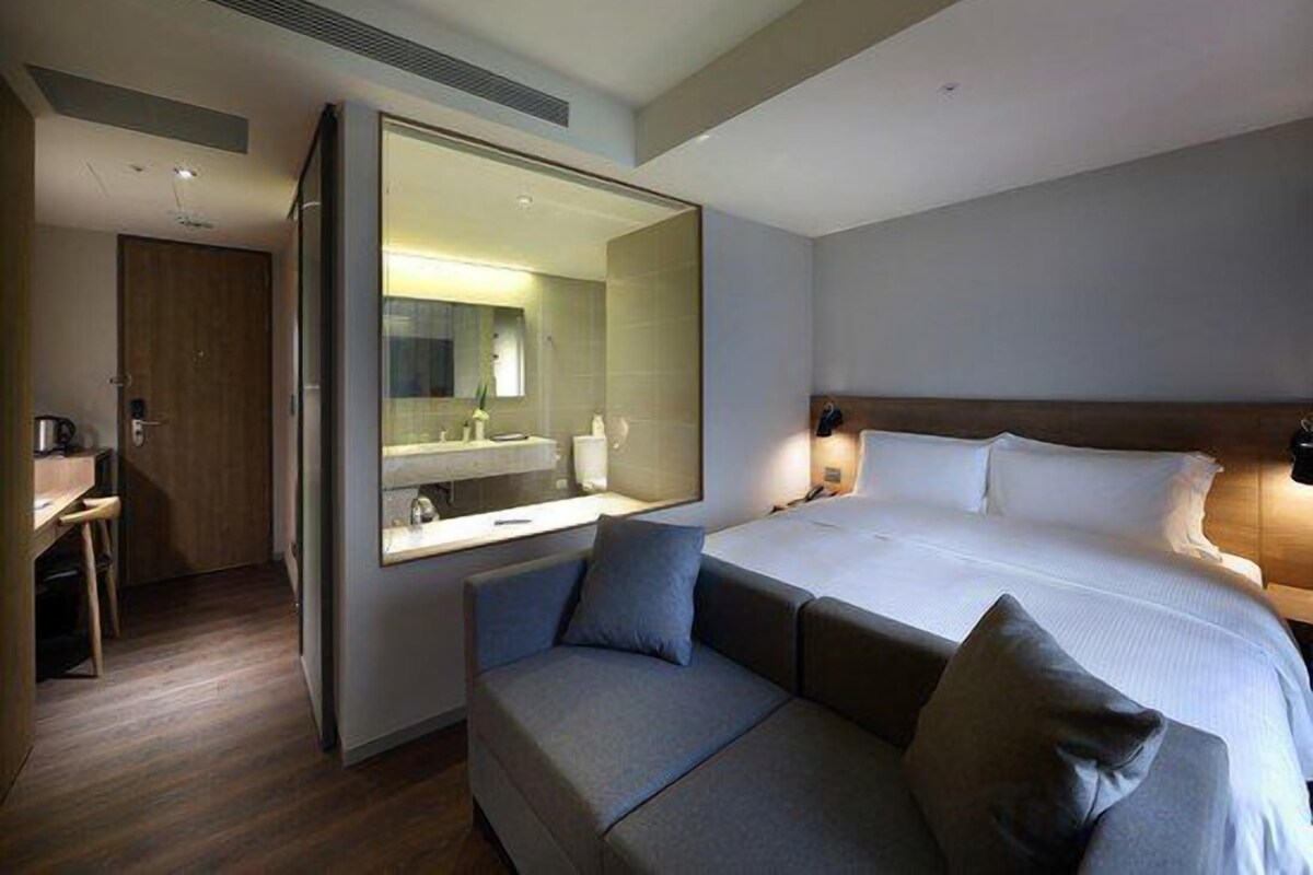 A hotel room with a bed, a sofa, a desk, and a large mirror.