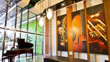 Una hall moderna con un pianoforte a coda, una panca e un'ampia opera d'arte a parete raffigurante strumenti musicali.