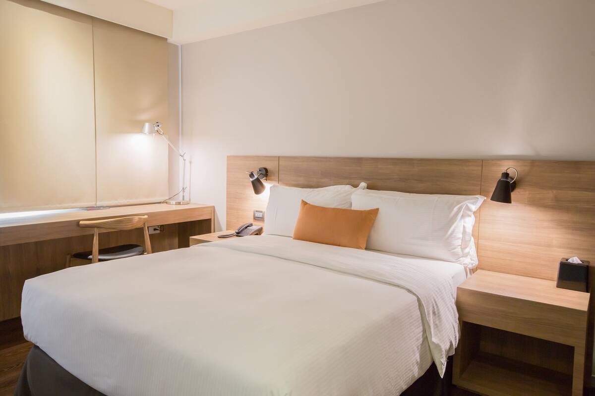 Una camera d'albergo ben ordinata con un letto grande, comodini, una scrivania e una sedia.