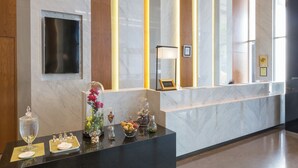 Un comptoir d’accueil avec un dessus en marbre, une vitrine en verre contenant des fleurs et un certificat encadré accroché au mur.