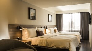 Une chambre d’hôtel avec un grand lit, un canapé, une télévision et une fenêtre avec des rideaux.