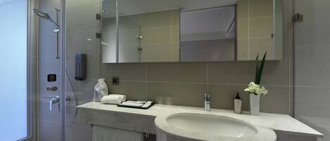 A modern bathroom with a glass-enclosed shower, a marble sink, and a large mirror.