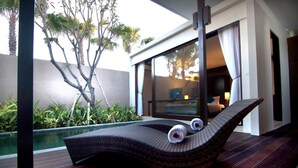 A sun lounger with two towels, a pool, and a view of a bedroom with a bed and curtains. - Asa Bali Luxury Villas & Spa (Seminyak)