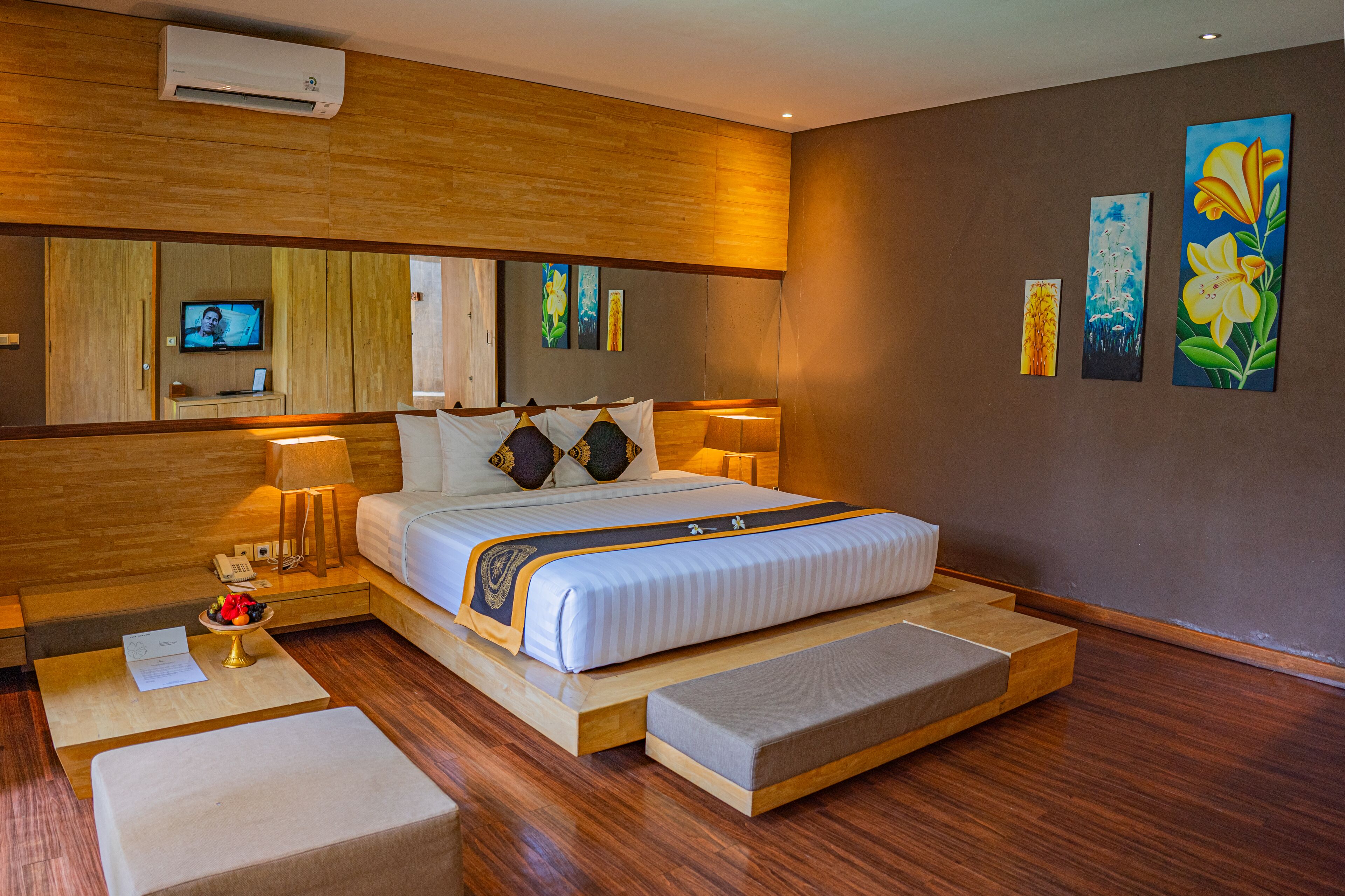 Ein modernes Hotelzimmer mit einem großen Bett, Nachttischlampen, Holzboden und Bildern an den Wänden.