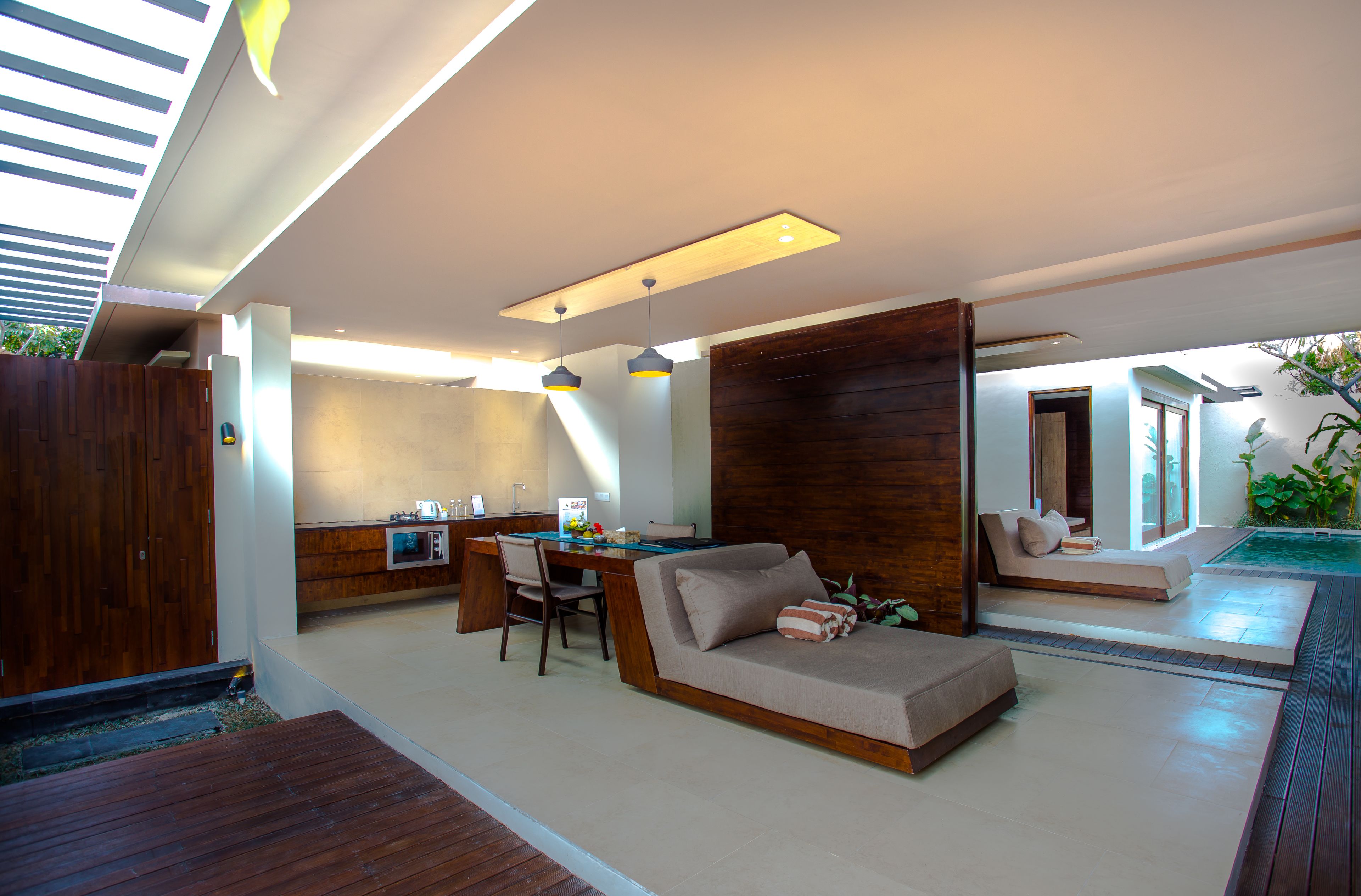 Un espacio moderno con sofá, mesa de comedor y zona de estar junto a la piscina.