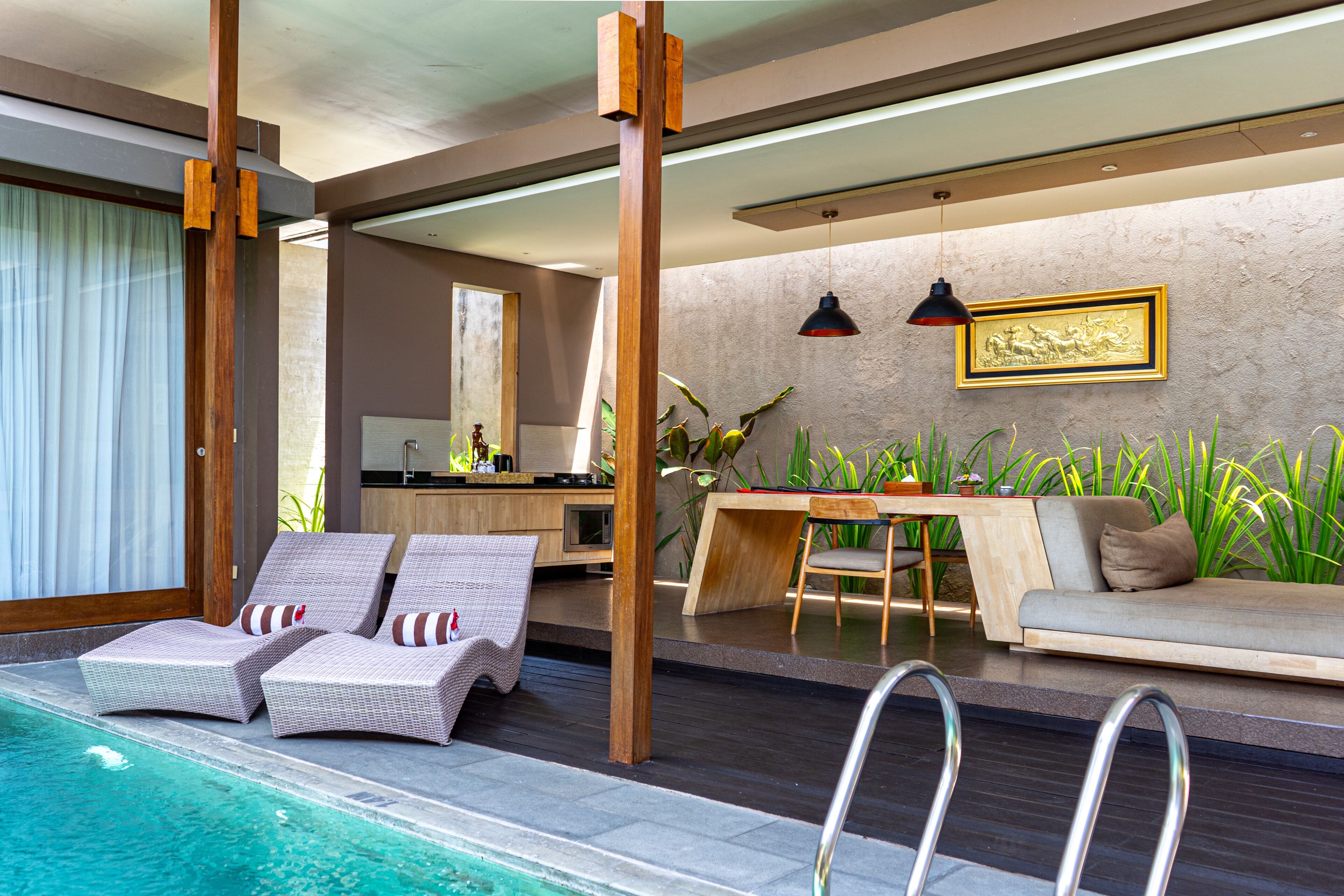 A modern indoor pool area with lounge chairs, a dining table, and a sofa.