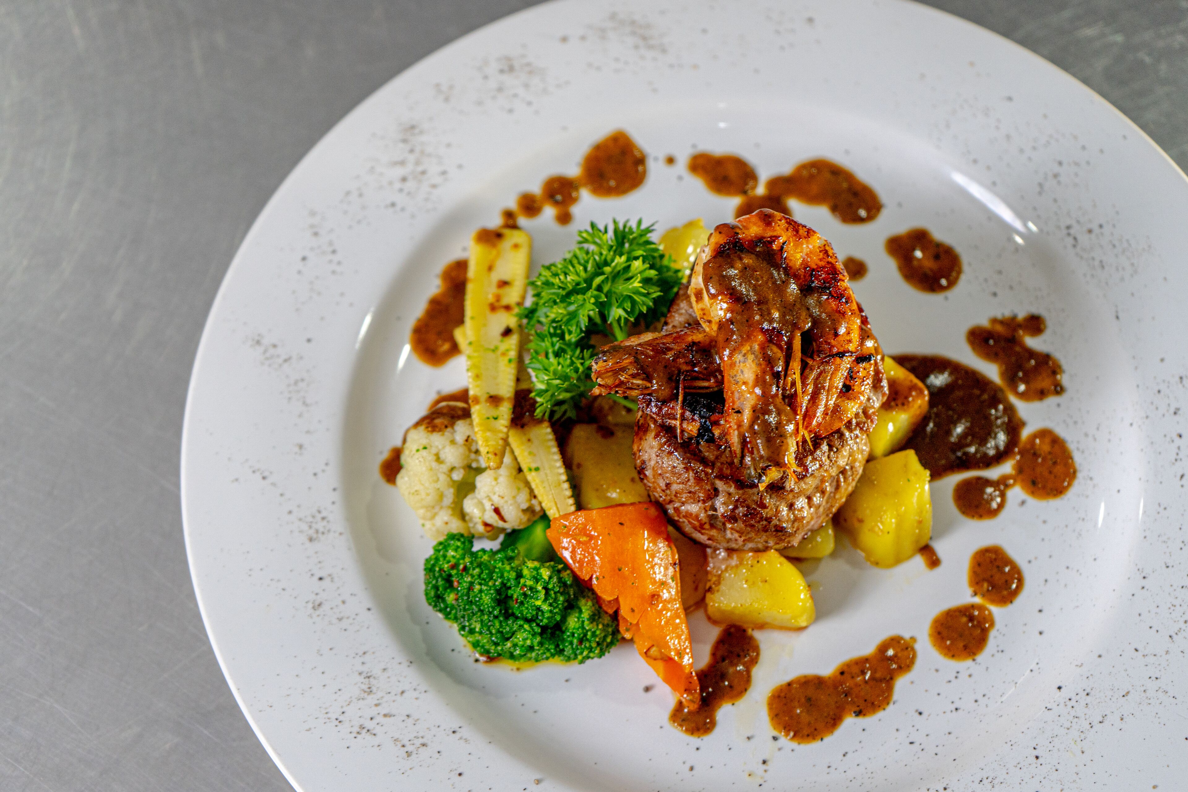 A plate of food with a piece of meat, vegetables, and sauce.