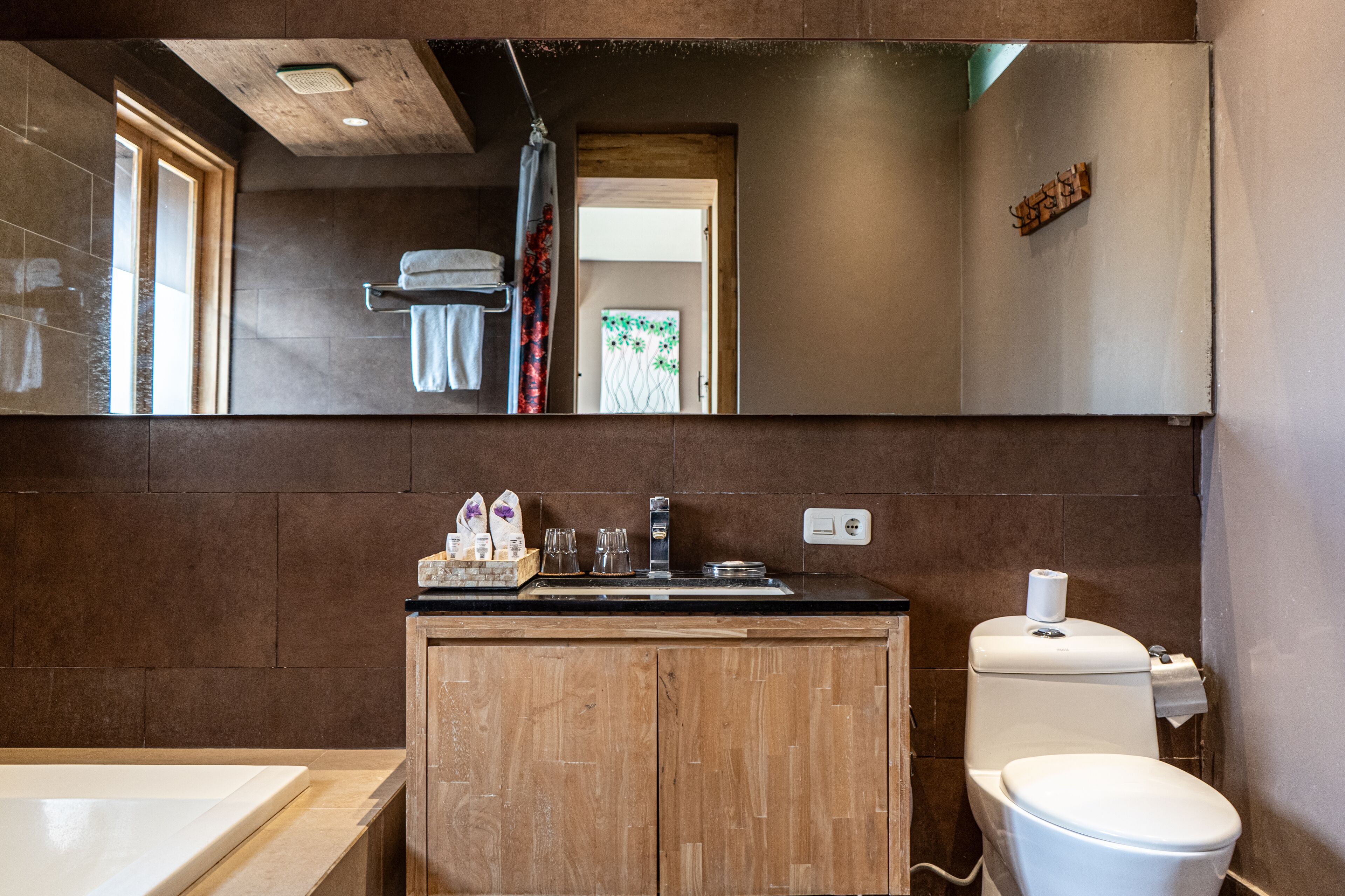 A bathroom with a wooden vanity, a sink, a toilet, and a large mirror.