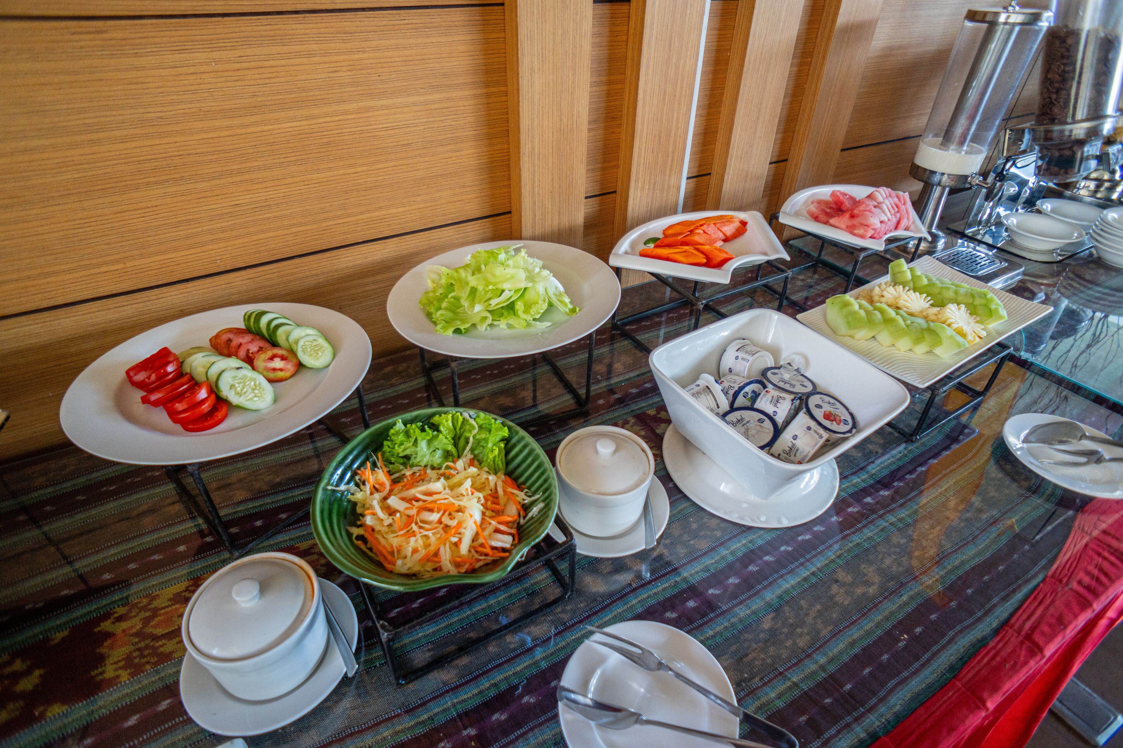 Un buffet proposant divers plats, notamment des légumes, des salades et un saladier de carottes râpées.