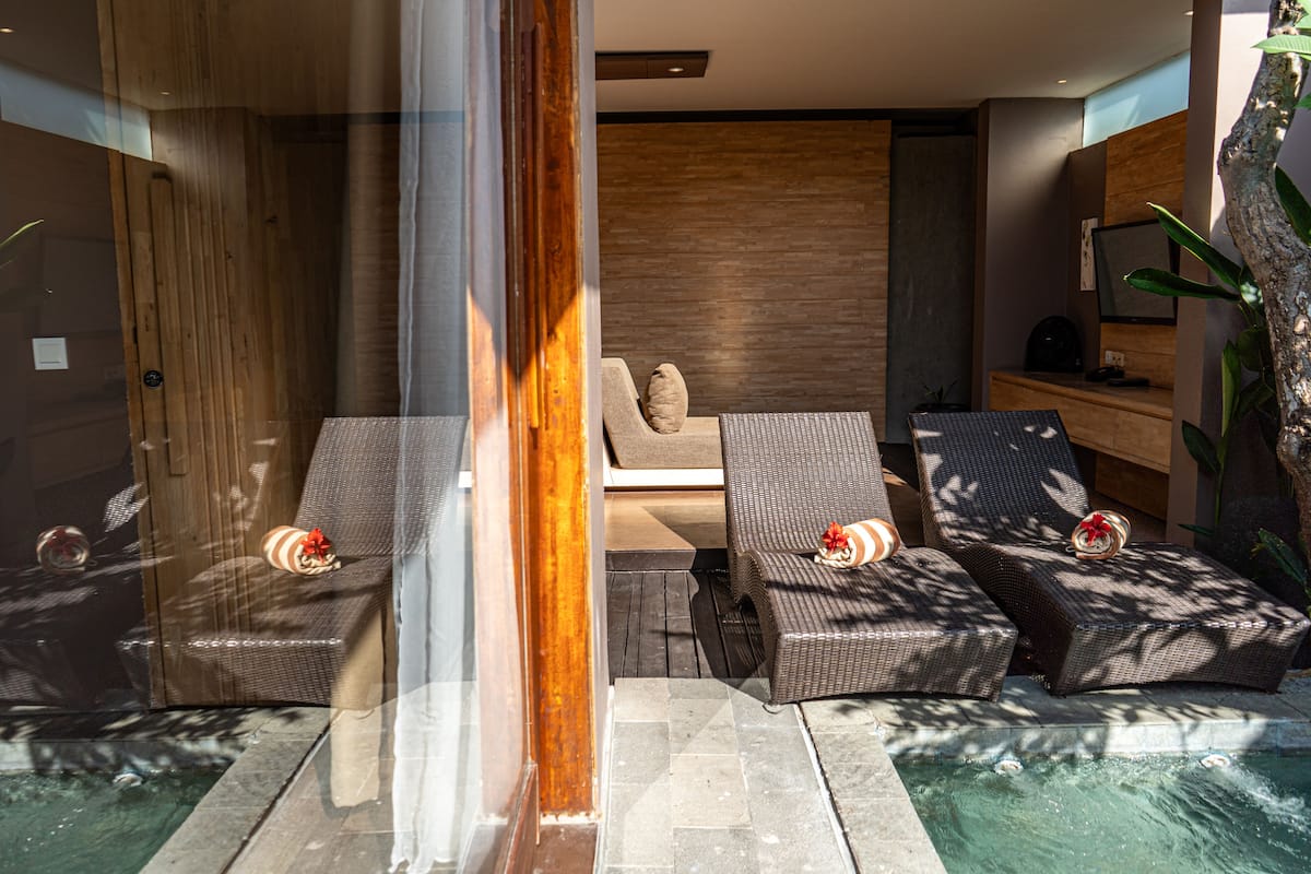Een modern binnenzwembad met ligbedden en een loungebank, een houten wand en een receptiebalie.