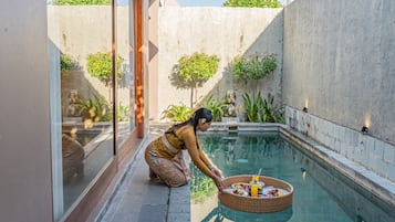 Guests can enjoy a serene poolside setting surrounded by lush greenery and a low wall.